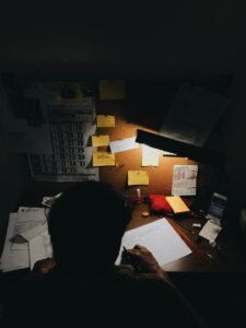 Person scanning receipts beside labeled folders, a calculator, notebook, and laptop on a tidy desk.