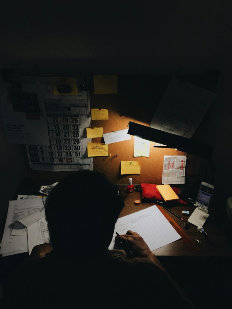 Person scanning receipts beside labeled folders, a calculator, notebook, and laptop on a tidy desk.